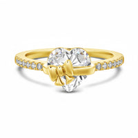 Gold ring with heart-shaped diamond and bow design on a white background