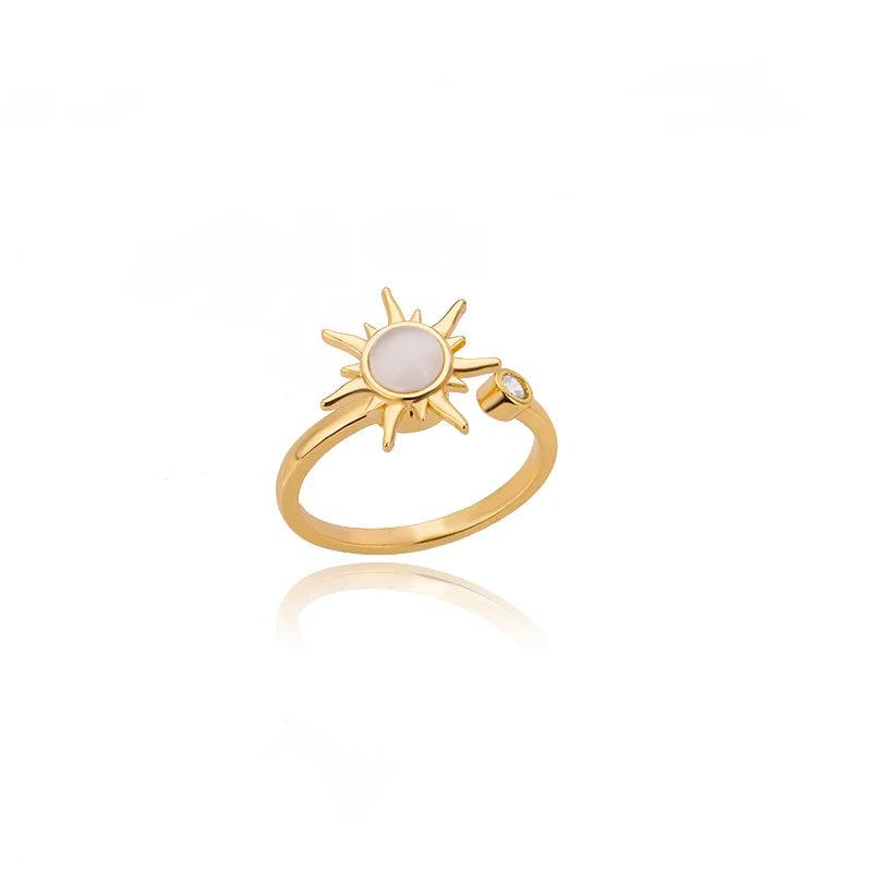 Gold ring with sun design and pearl center on a white background